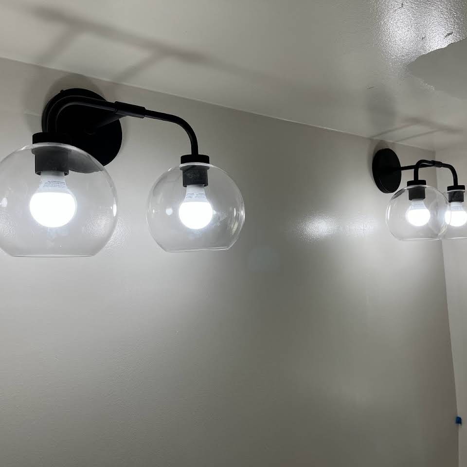 Black globe vanity sconces installed and lit