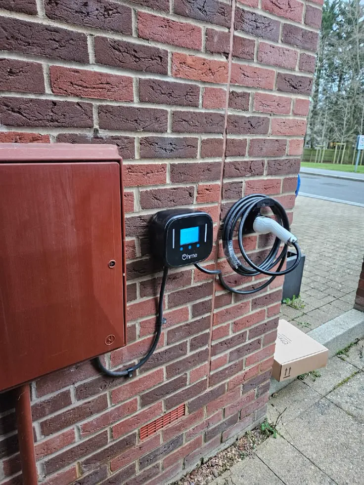 Home EV charger mounted on an exterior brick wall in Castle Rock with the charging cable neatly stowed